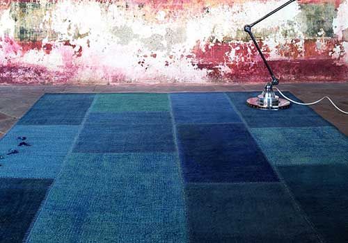 Eine Lampe steht auf einem blauen Teppich vor einer rosa Wand.