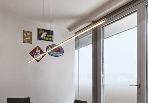 Ein Esszimmer mit einem Tisch und Stühlen und einem Fenster mit einer Lampe, die von der Decke hängt.