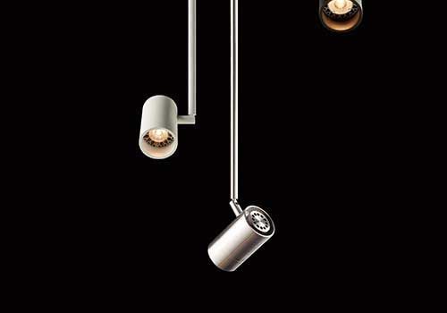 Vor einem schwarzen Hintergrund hängen drei Lichter von der Decke.