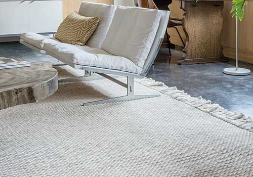 In einem Wohnzimmer steht ein Stuhl auf einem Teppich neben einem Sofa.