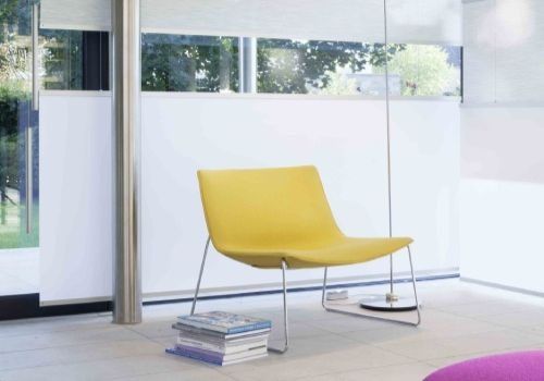 Ein gelber Stuhl in einem Wohnzimmer neben einem Stapel Bücher