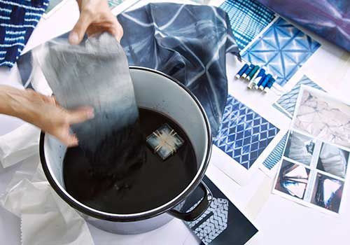 Eine Person hält ein Stück Stoff in eine Schüssel mit Wasser.