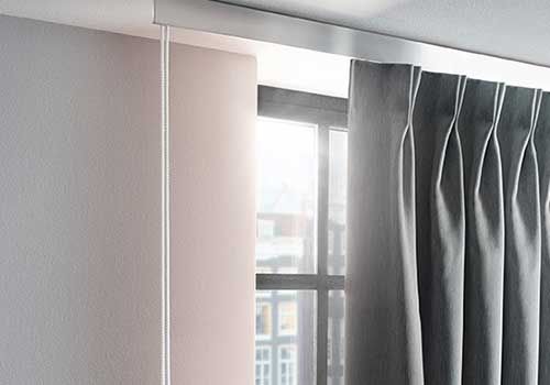 Eine Nahaufnahme eines Fensters mit Vorhängen, die von der Decke hängen.