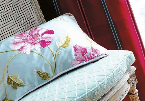 Auf einem Stuhl liegt ein blaues Kissen mit rosa Blumen darauf.