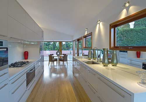 Eine lange Küche mit weißen Schränken und Holzböden