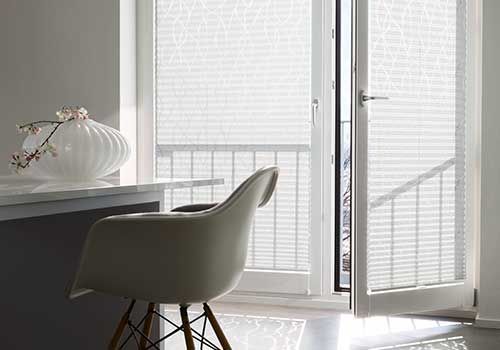 Ein Stuhl steht vor einem Fenster mit Jalousien.