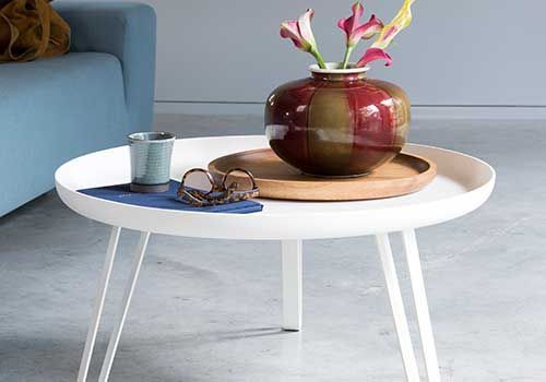 Ein weißer Couchtisch mit einer Blumenvase darauf.