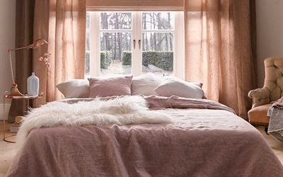 Ein Schlafzimmer mit Bett, Stuhl, Lampe und Fenster.