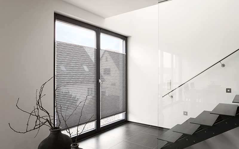 Ein Raum mit einer Treppe und einem Fenster mit Jalousien.