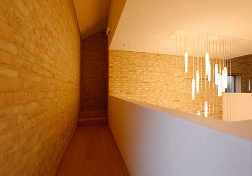 Ein langer Flur mit einer Backsteinmauer und einer Treppe, die in den zweiten Stock führt.