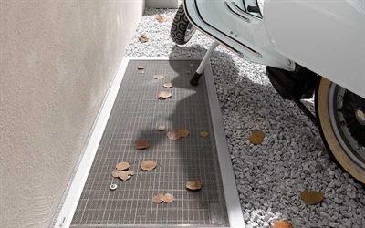 Ein weißer Motorroller ist in einer Einfahrt neben einer Mauer geparkt.