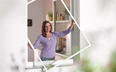 Eine Frau steht vor einem Fenster mit Fliegengitter.