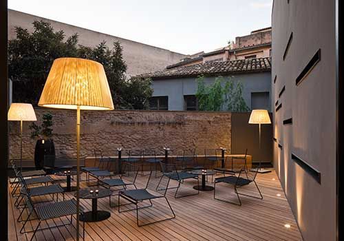 Eine Terrasse mit Tischen, Stühlen und Lampen darauf