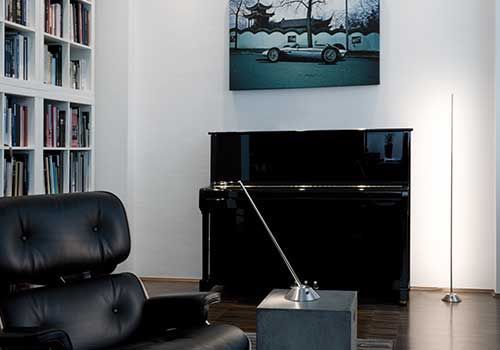 Ein Wohnzimmer mit einem Stuhl, einem Klavier und einem Gemälde eines Rennautos an der Wand.