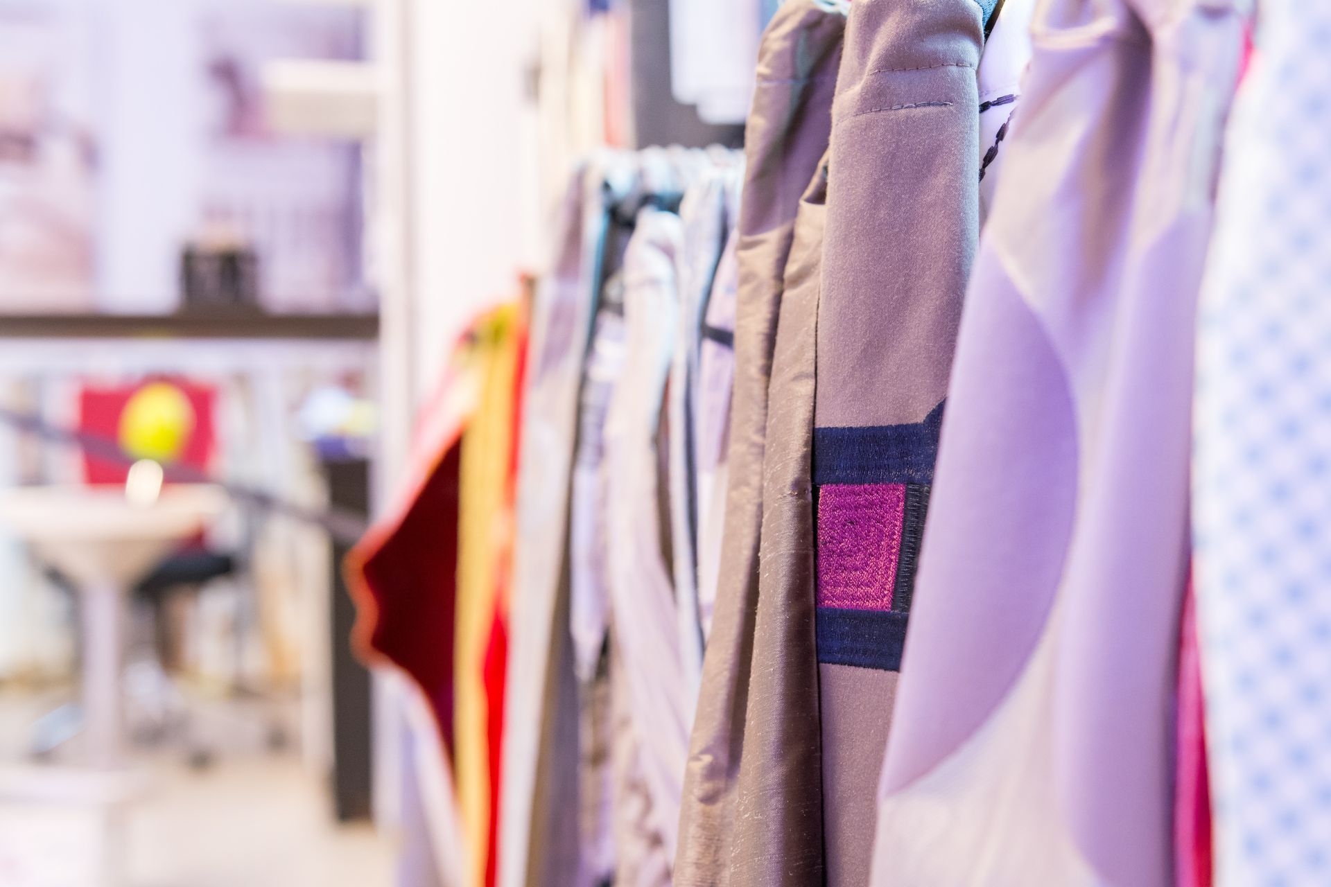 Eine Reihe von Kleidungsstücken, die in einem Geschäft an einer Stange hängen.