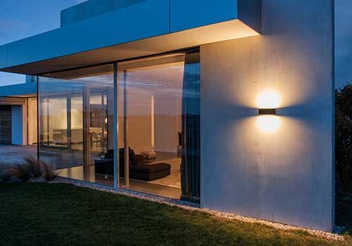 Ein modernes Haus mit vielen Fenstern und einem Licht an der Seite.