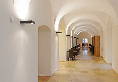 Ein langer Flur mit gewölbten Decken und Tischen und Stühlen.