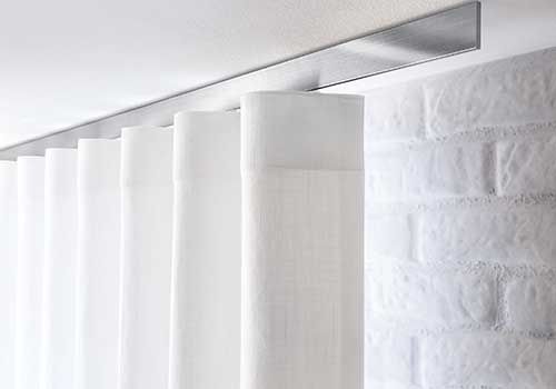 Ein weißer Vorhang hängt von der Decke neben einer weißen Ziegelwand.