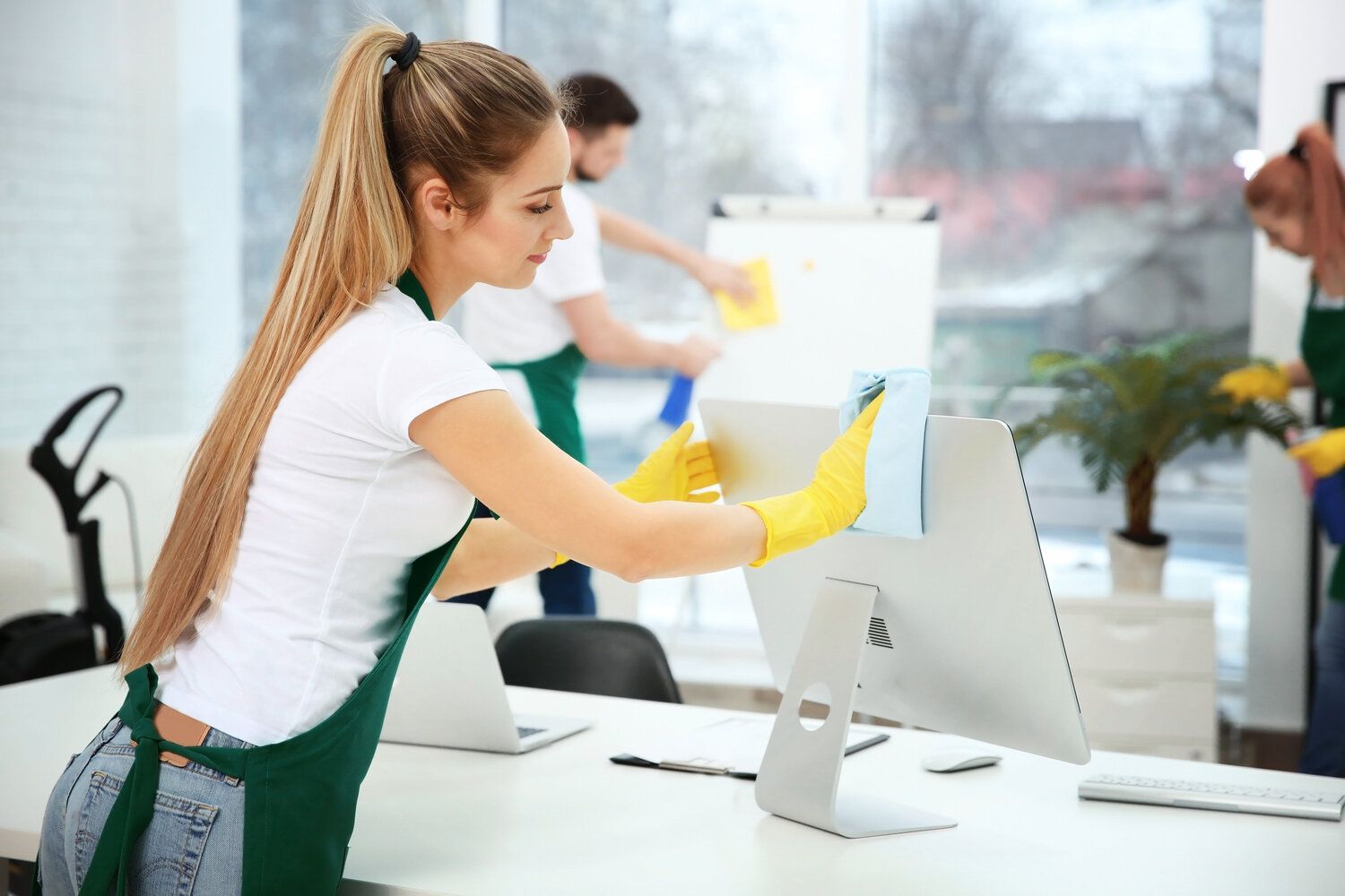 Una mujer está limpiando un monitor de computadora en una oficina.