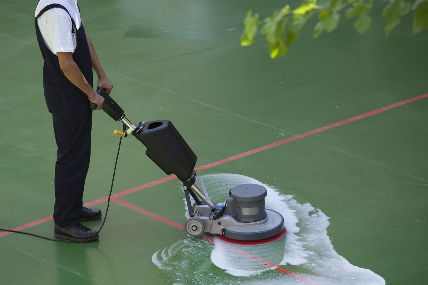 Un hombre está usando una máquina para limpiar una cancha de tenis.