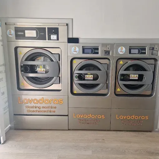 Tres lavadoras de acero inoxidable en una lavandería; las palabras 