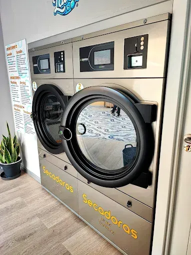 Dos secadoras de ropa comerciales con las puertas abiertas, en una lavandería de autoservicio.