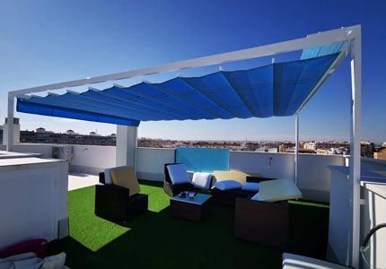 Un patio en la azotea con un toldo azul encima.