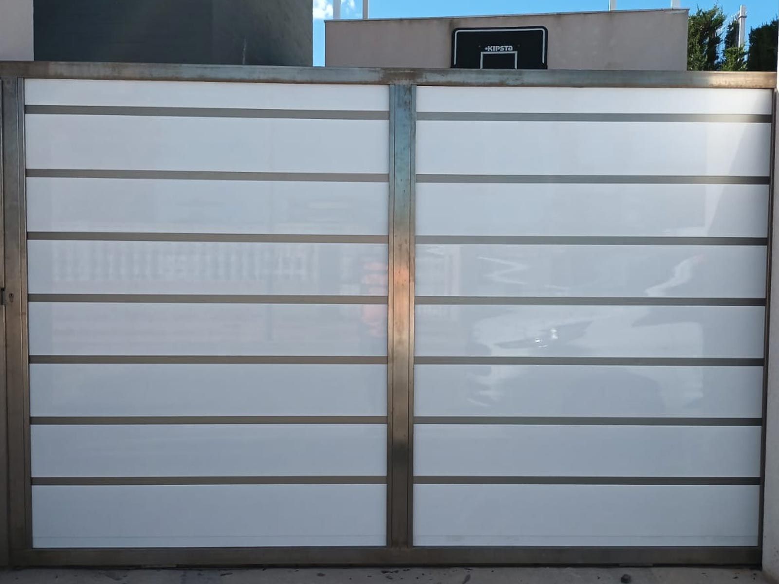 Una puerta blanca con marco de acero inoxidable se encuentra frente a un edificio.