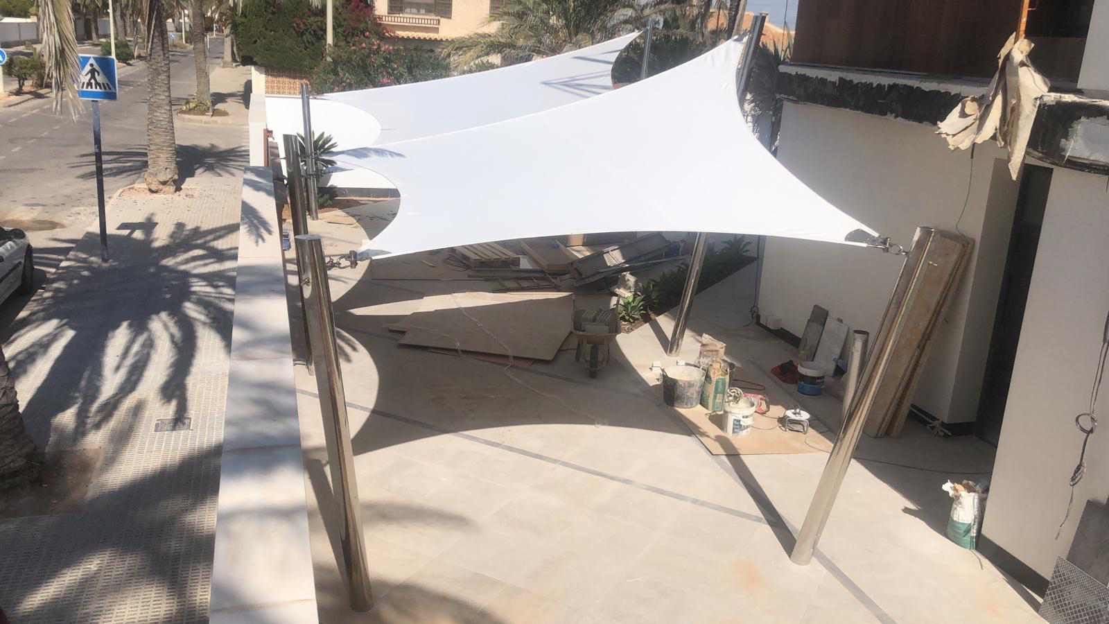 Una gran sombrilla blanca está delante de un edificio.