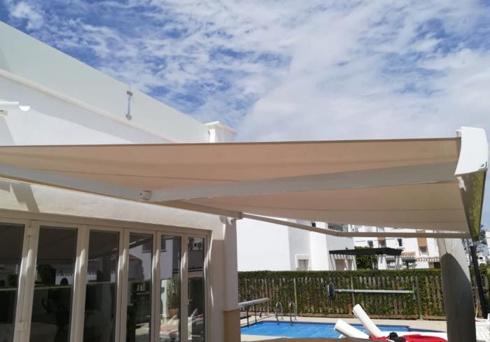 Una casa blanca con un gran toldo sobre una piscina.