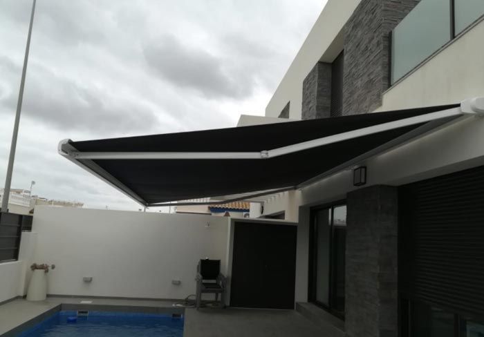 Una casa con piscina y un toldo sobre ella