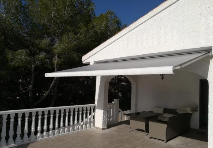 Una casa blanca con un balcón con un toldo blanco encima.