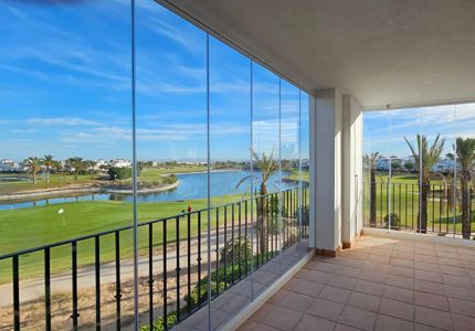 Un balcón con vista a un campo de golf y un lago.