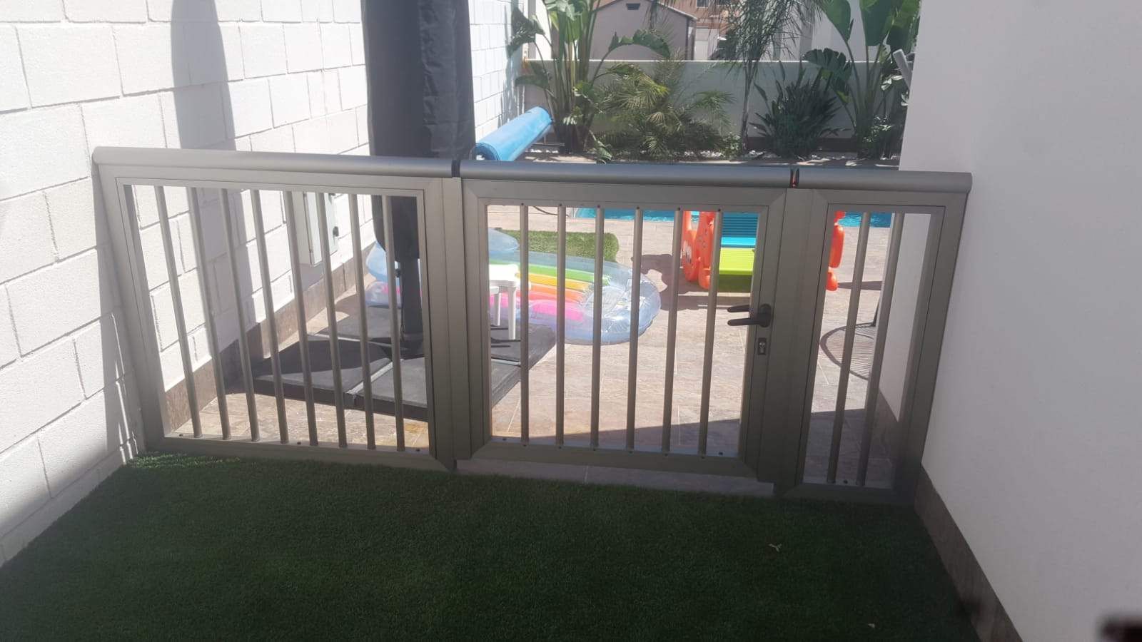 Una puerta de metal se encuentra encima de un exuberante césped verde.