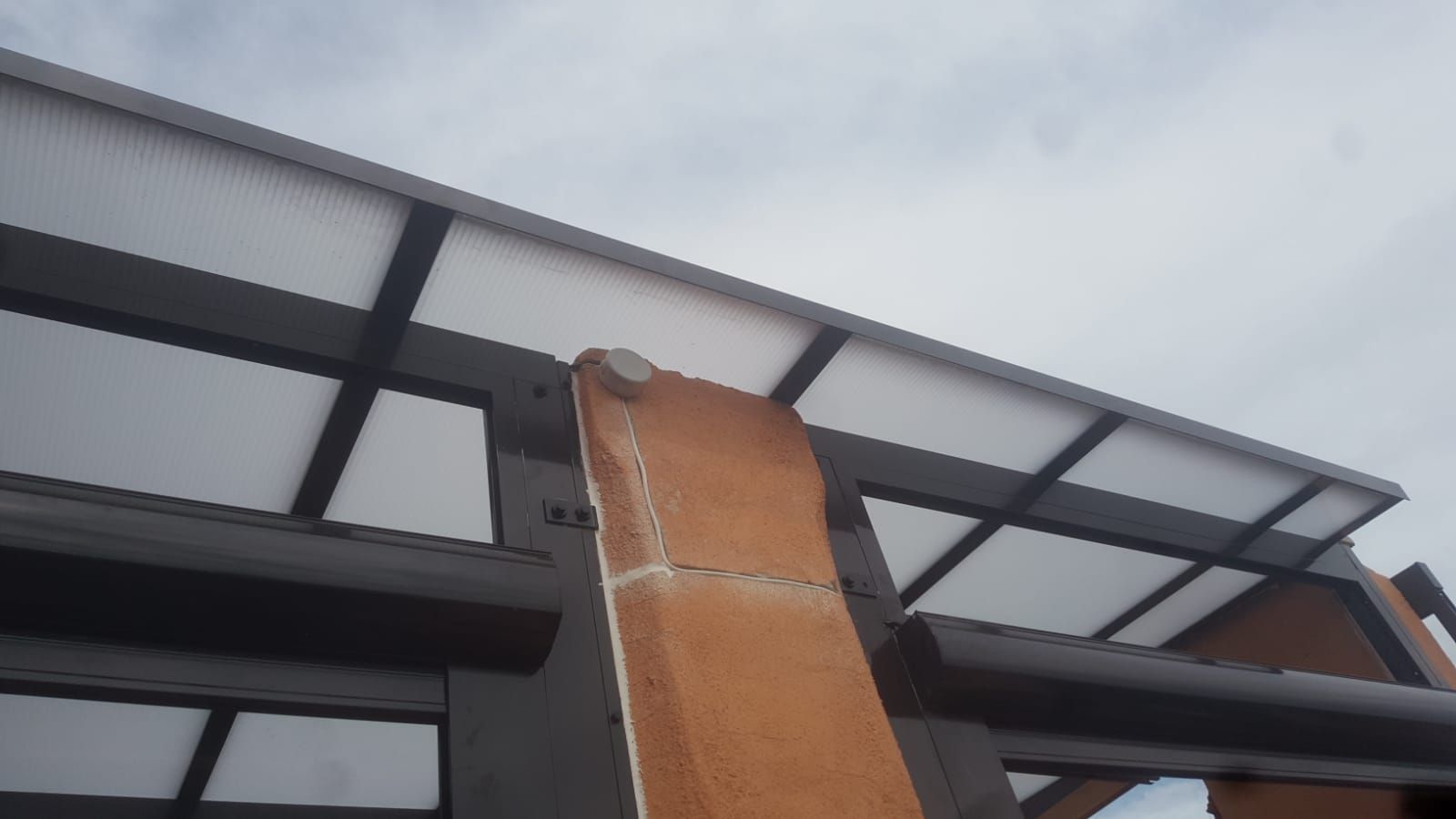 Una escalera de madera está apoyada contra un edificio con techo transparente.