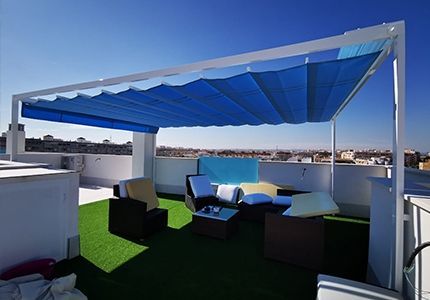 Un patio en la azotea con un toldo azul encima.