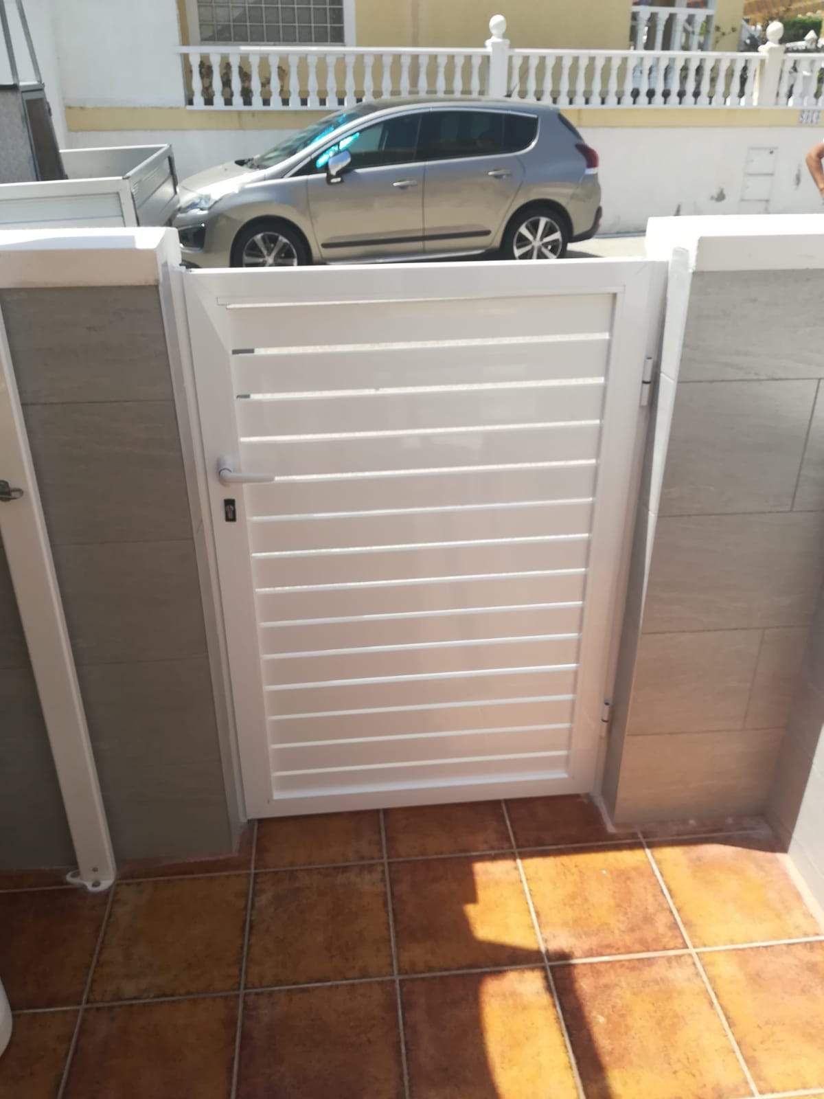 Un coche está aparcado detrás de una puerta blanca.