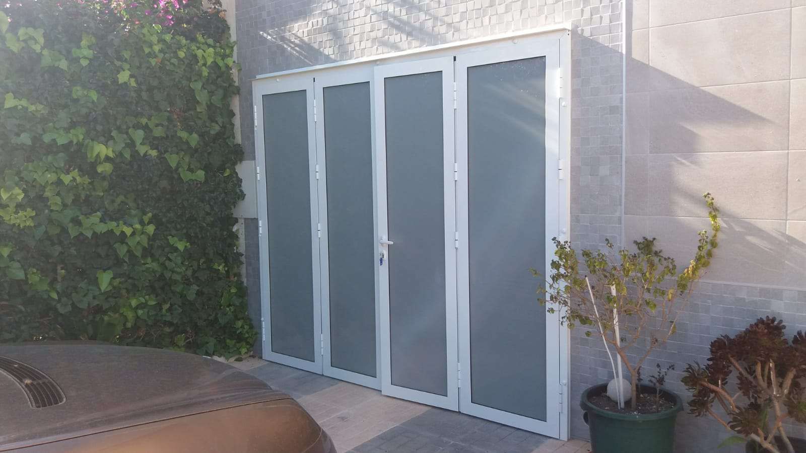 Una puerta blanca con una planta en una maceta al lado.