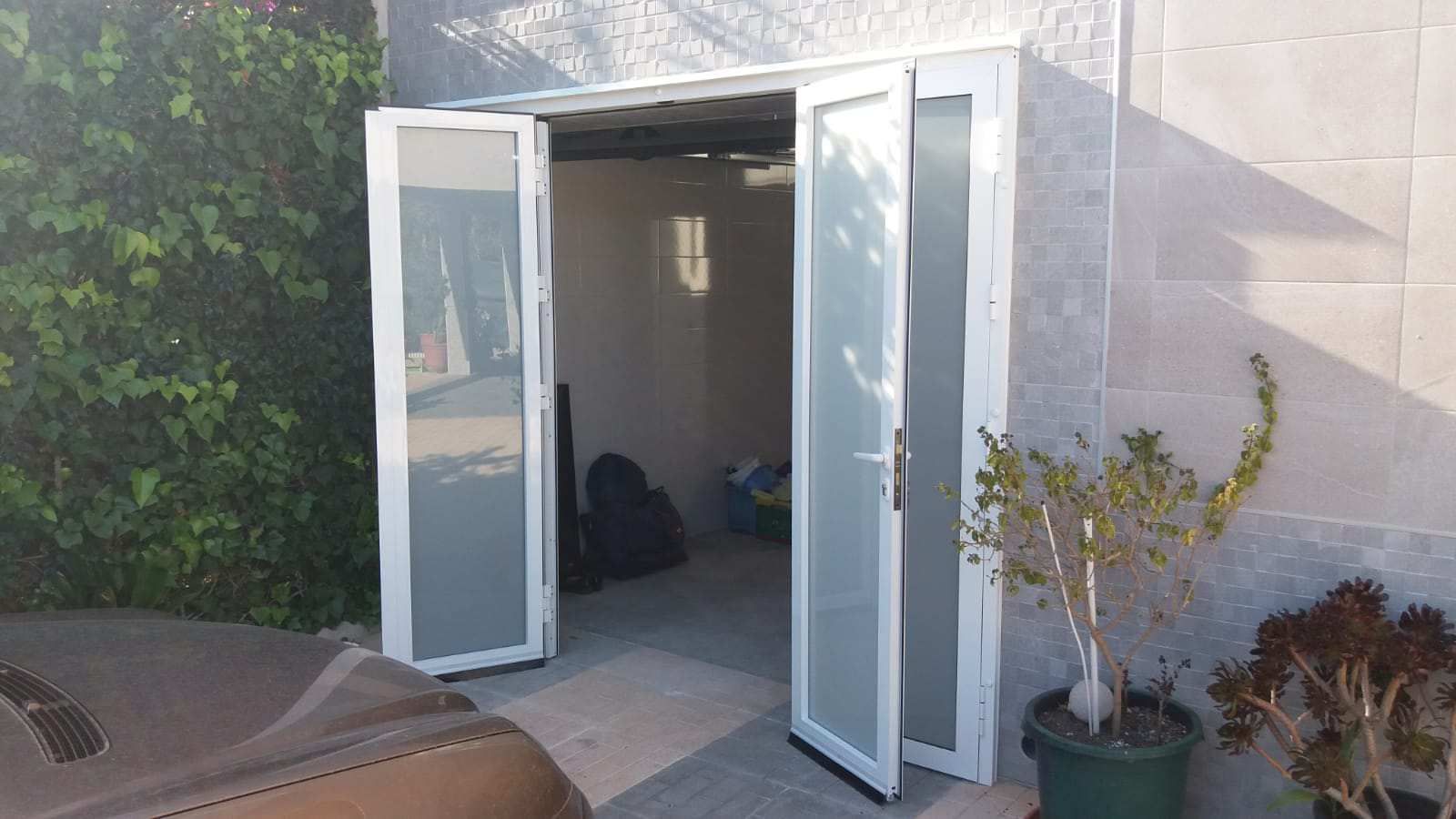 Una puerta blanca está abierta a una habitación con una planta delante de ella.