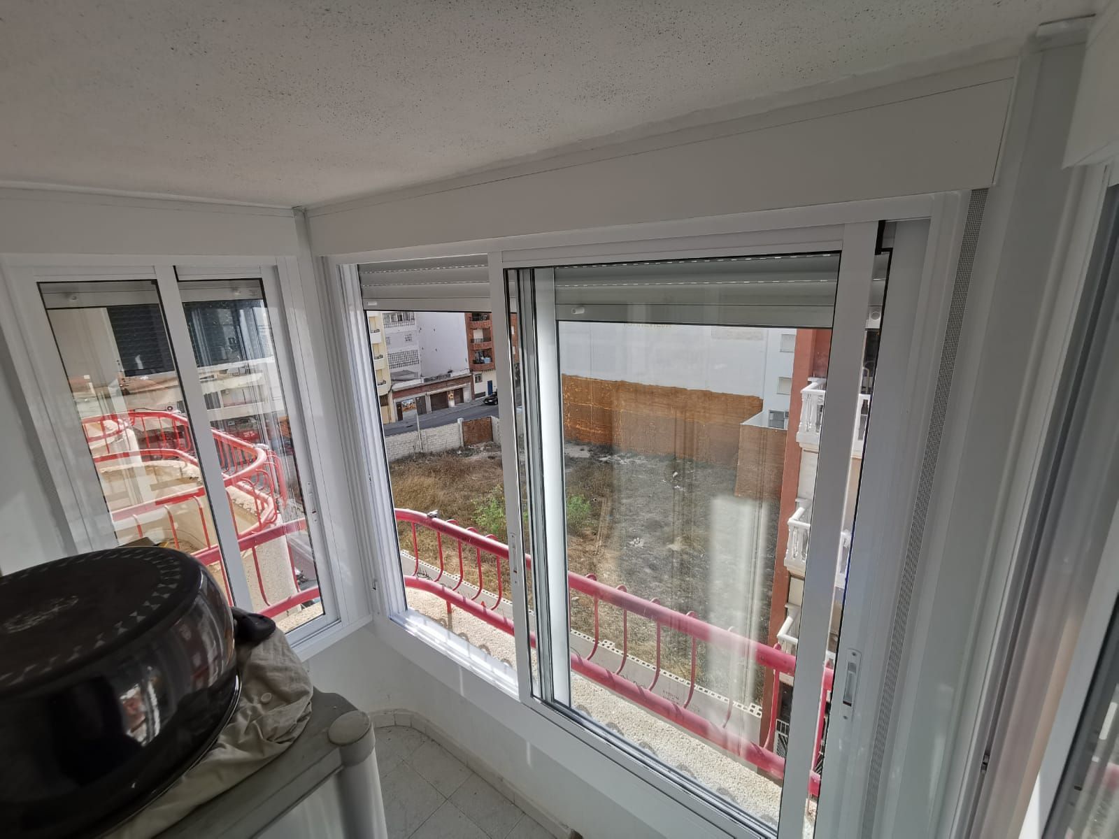 Una habitación con muchas ventanas y una maleta en el suelo.