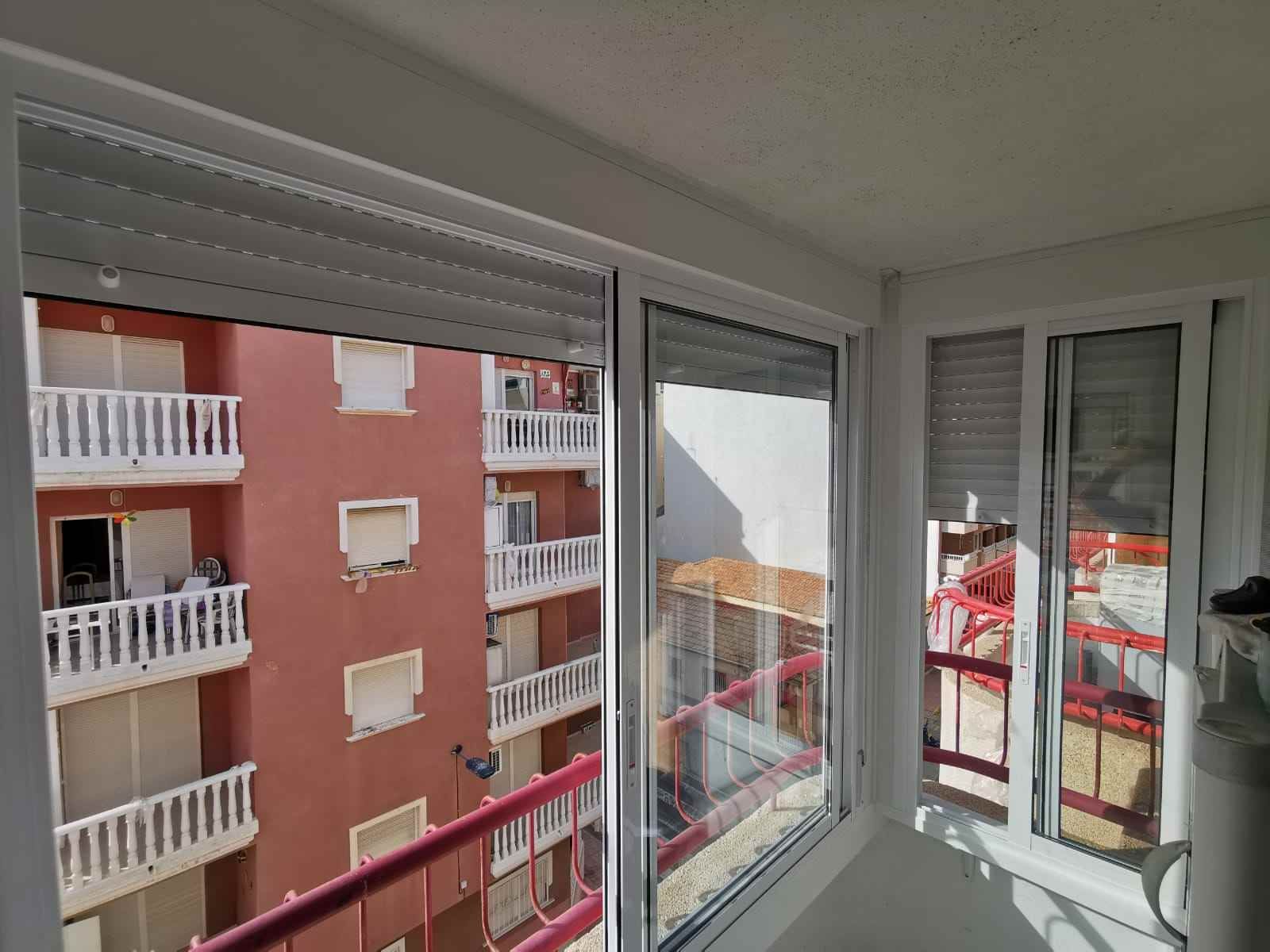 Un balcón con vista a un edificio desde una ventana.