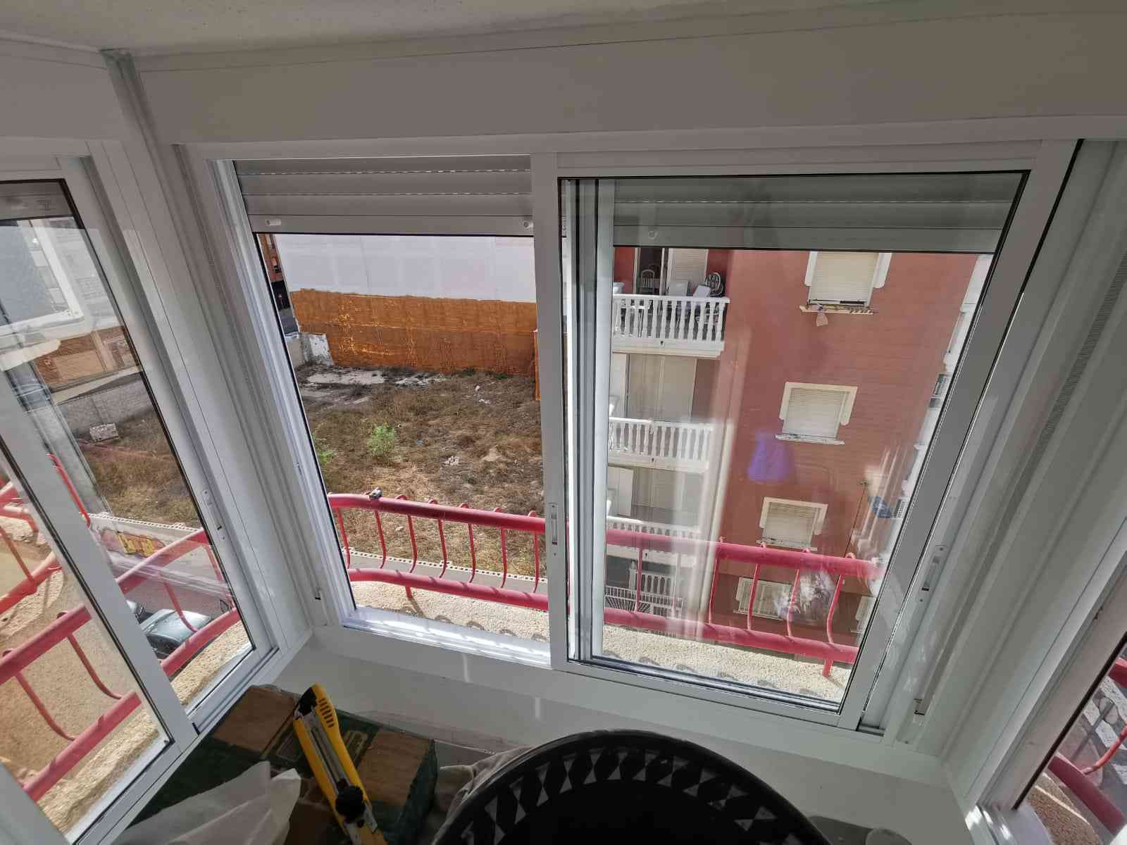 Un gran ventanal con vista a un edificio y un balcón.