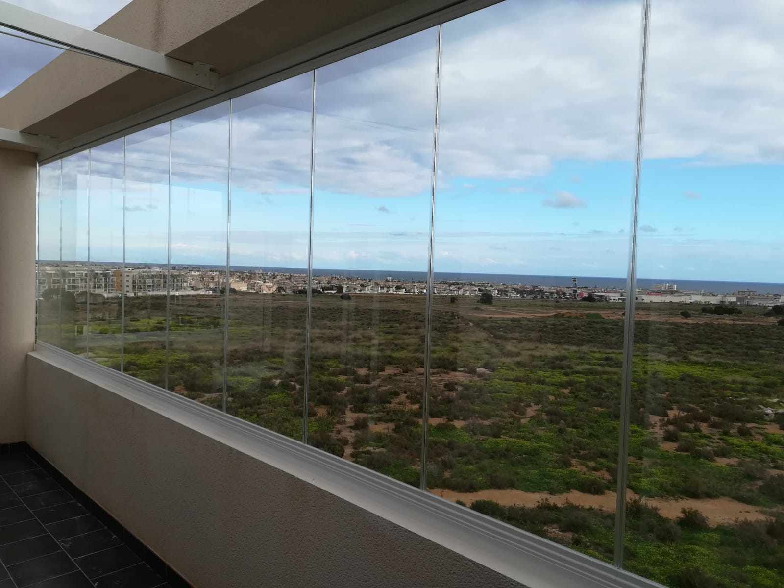 Un balcón con vista a un campo y al océano.