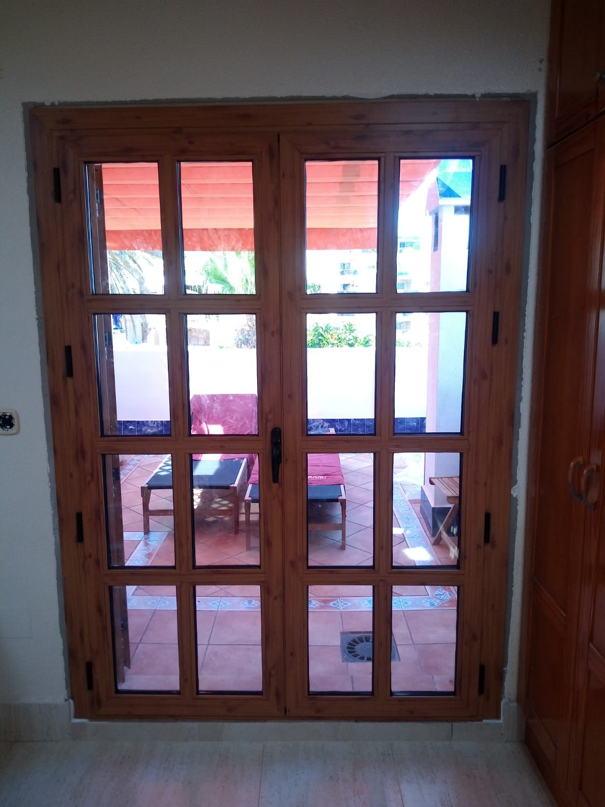 Una puerta de madera con muchas ventanas que dan a un patio.