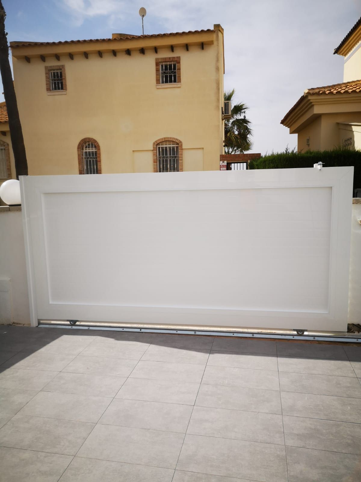 Una valla blanca con una casa al fondo.