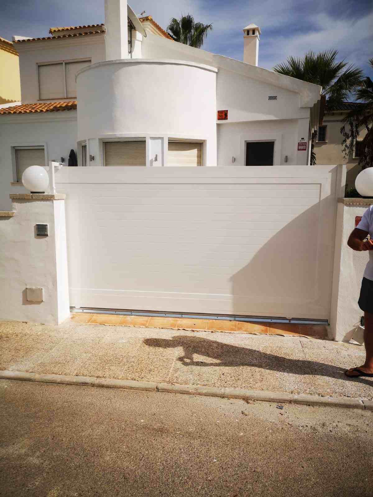 Un hombre está parado frente a una casa blanca con una puerta corrediza.