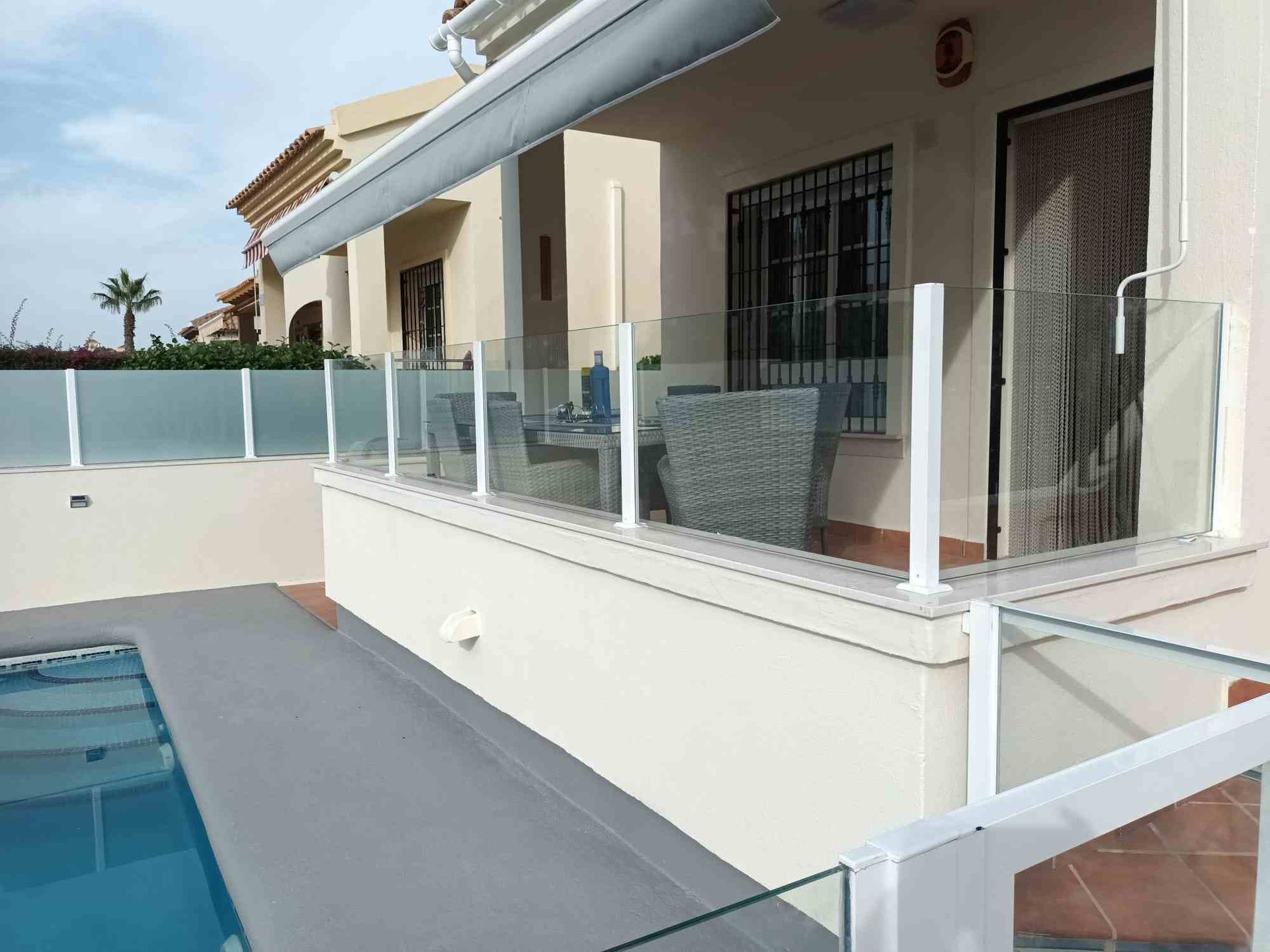 Una casa con piscina y una valla de cristal a su alrededor.