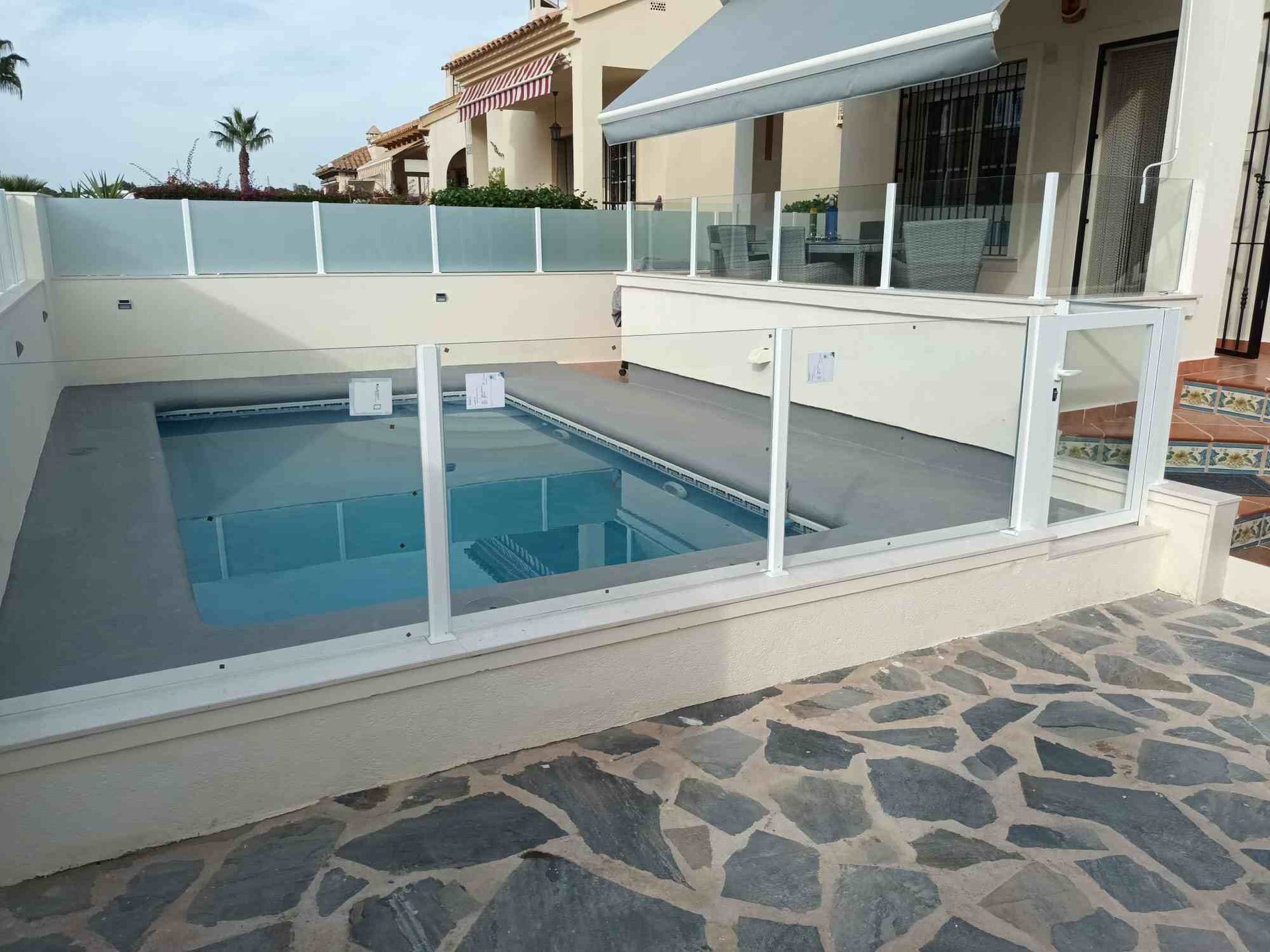 Una gran piscina está rodeada por una valla de cristal.