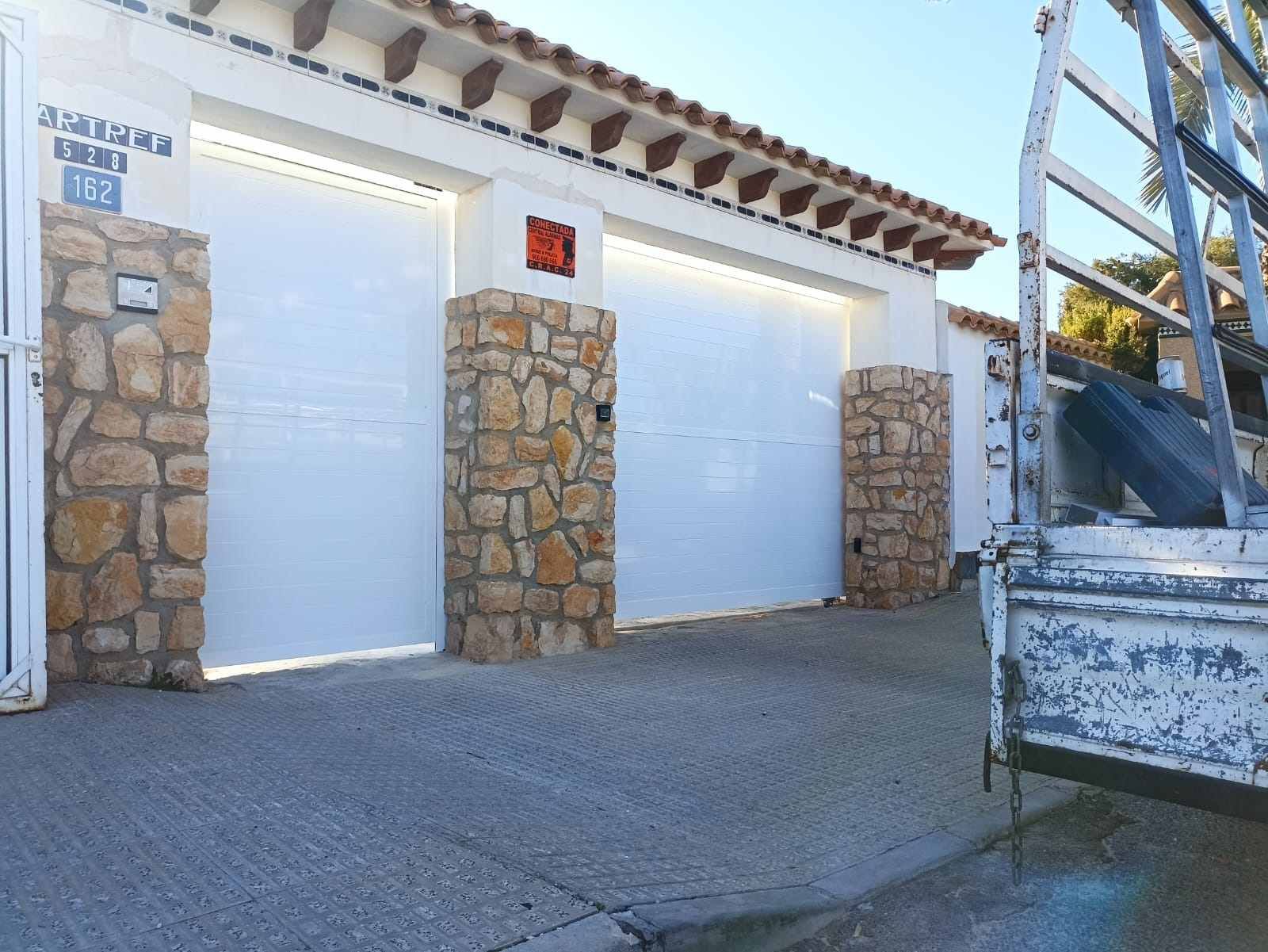 Un camión blanco está estacionado frente a una puerta de garaje blanca.