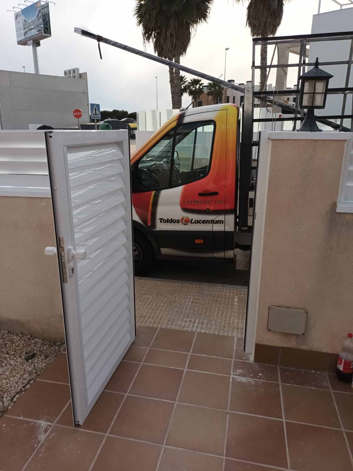 Una furgoneta amarilla y naranja está estacionada junto a una puerta blanca.